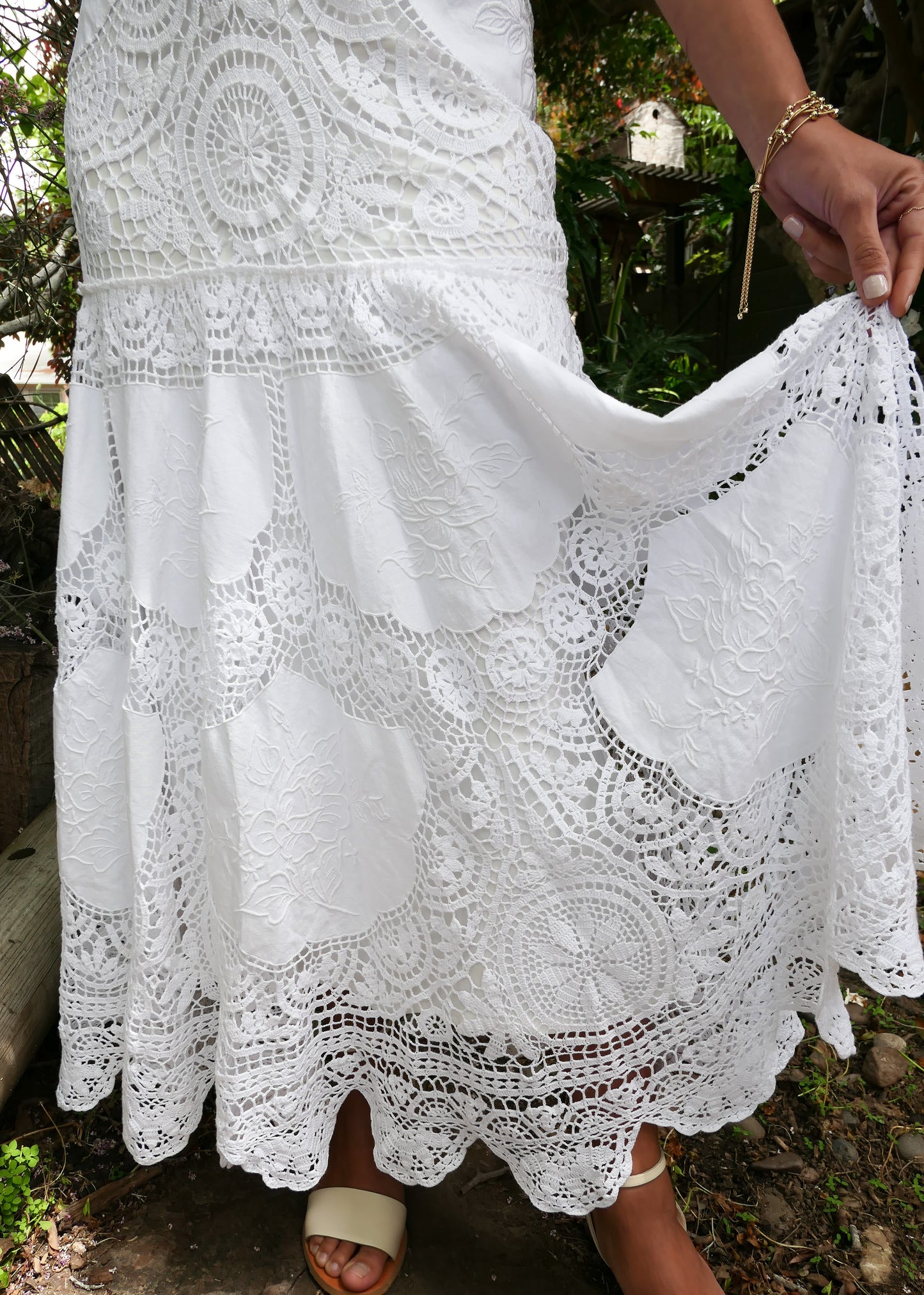 A romantic and elegantly seductive V-neck and V-back hand crocheted and embroidered patchwork maxi dress made with our signature Lim's Vintage fabric. This dress is fitted and flared at all the right places, accentuating your natural curves and perfect for your special wedding day or stylish summer beach party. Does not come with a slip, but we highly recommend wearing one due to the "holey" nature of the crochet. Color: White. Can be made to order. Closeup of dress.