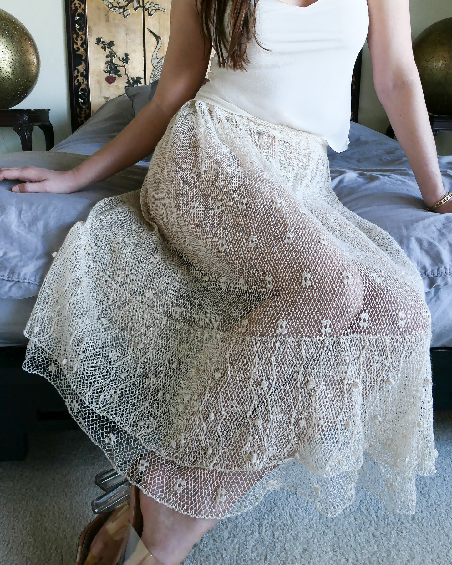 Closeup of skirt. Like the delicate petals of the California Poppy, this skirt wafts and floats like a gentle summer breeze. Made with a delicate fishnet crochet, dotted with mini florettes, and accented with a two-tiered ruffle hem, this dress is sure to sweep you off your feet! Comes with a comfortable fitting elastic waistband that rests easily on the waist. Great as a beach coverup with a pair of wedgy sandals, a cute straw hat, and a mojito in hand. Size: Fits small to medium