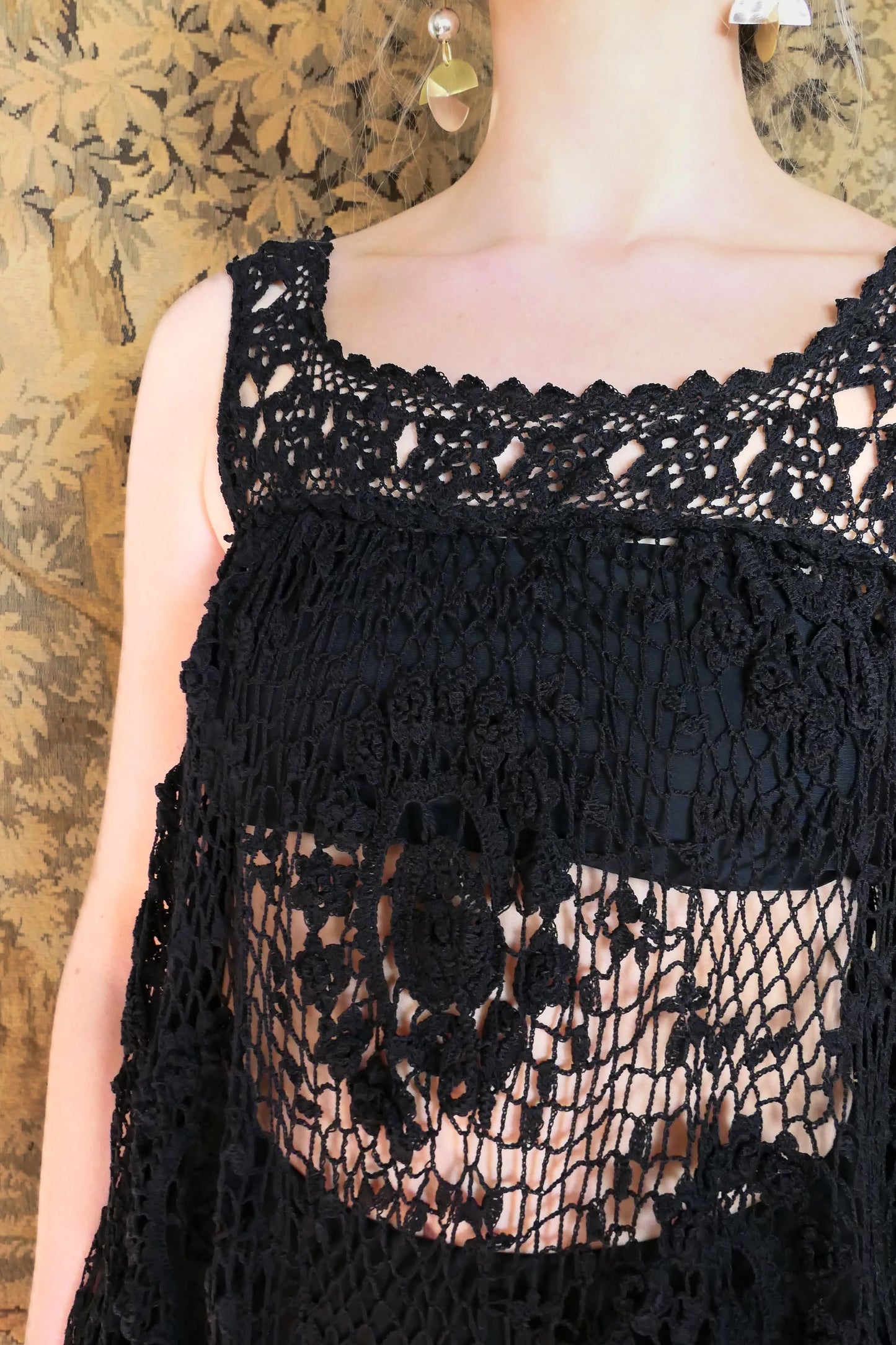 Closeup of front of dress and neckline. Loose elastic band above the bust area and under the armpits. A sleeveless babydoll dress made from our Lim's Vintage original fishnet crochet fabric with a repeating floral themed design throughout. A versatile, comfortable, fun-to-twirl-around-in pullover dress that you can wear wherever you go. The area above the breast and under the armpits is elastic and stretchable, making the dress suitable for most sizes. Color: Black, Size: One size fits most