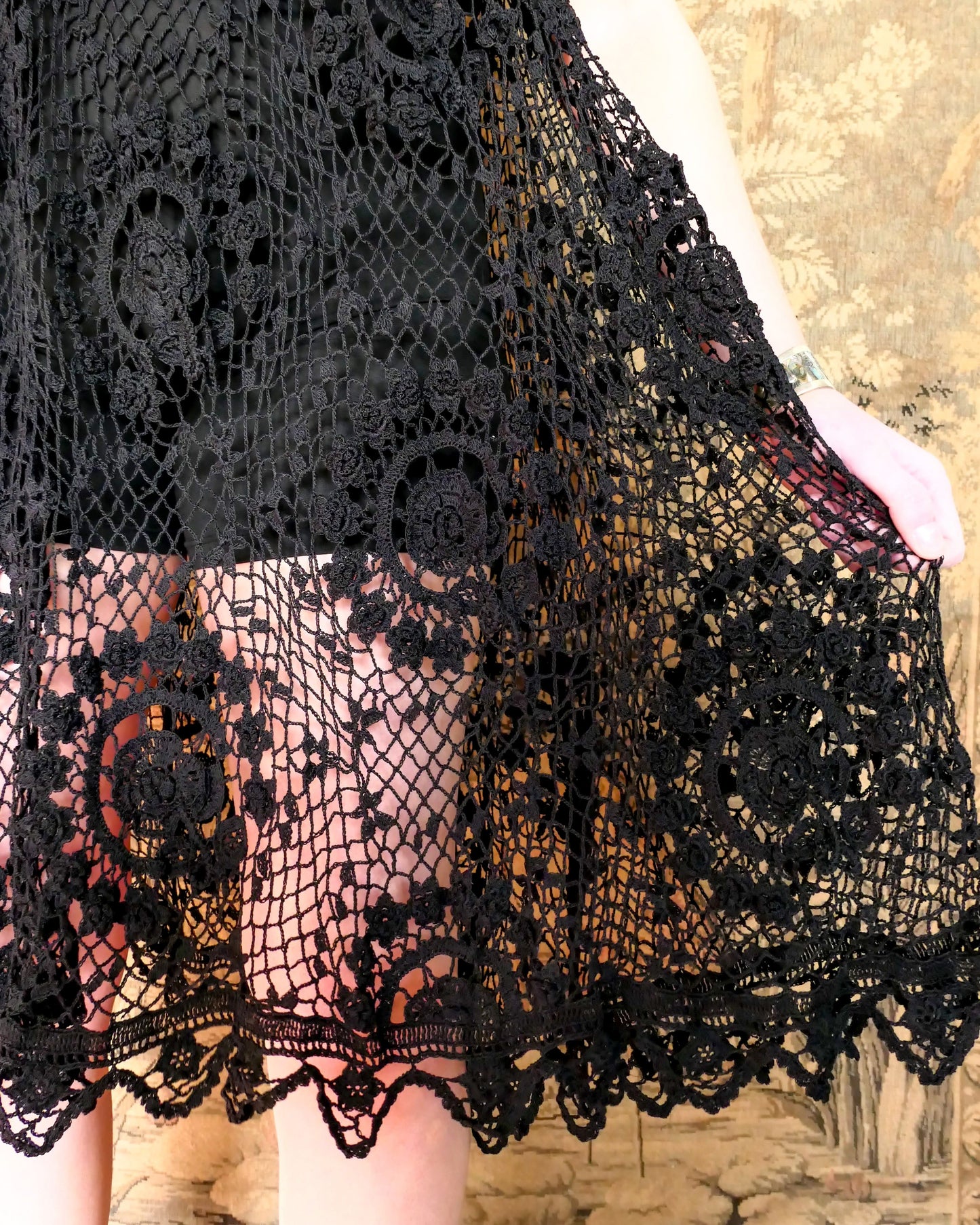 Closeup of crochet detail on the dress. A sleeveless babydoll dress made from our Lim's Vintage original fishnet crochet fabric with a repeating floral themed design throughout. A versatile, comfortable, fun-to-twirl-around-in pullover dress that you can wear wherever you go. The area above the breast and under the armpits is elastic and stretchable, making the dress suitable for most sizes. Color: Black, Size: One size fits most