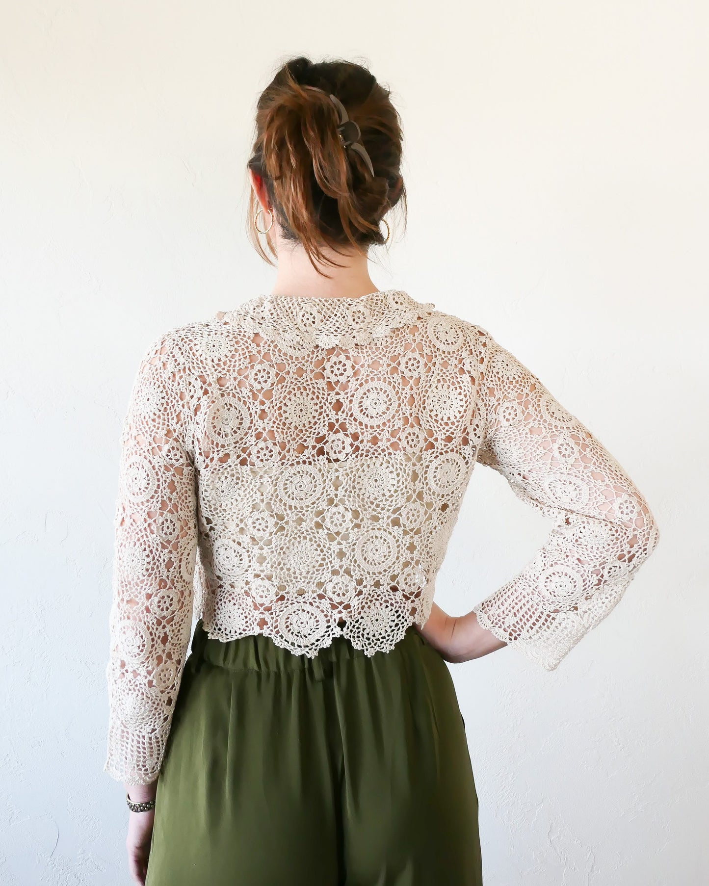 Back view of natural colored Lim's Vintage crochet crop top. A versatile and boho chic hand crocheted cropped cardigan sweater with a unique, repeating kaleidoscope-like floral pattern throughout.