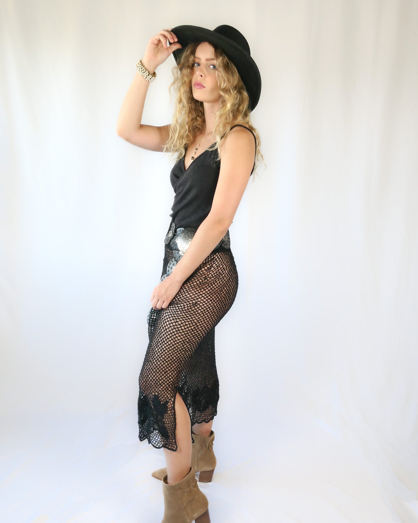 A Lim's Vintage 1980s original fishnet patterned skirt with intricate floral design and scalloped edging at the hem. Provocative with a bohemian vibe, this hand crocheted skirt goes well with everything and comes with a comfortable elastic waistband. Go rogue with boots and a cowboy hat, or wear it with heels and a silk camisole for a softer touch. Size: First Small to Medium Measurements: Small to Medium Waist 26"- 30" (elastic) Hip 40” Length 31” Color: Black Material: 100% ramie