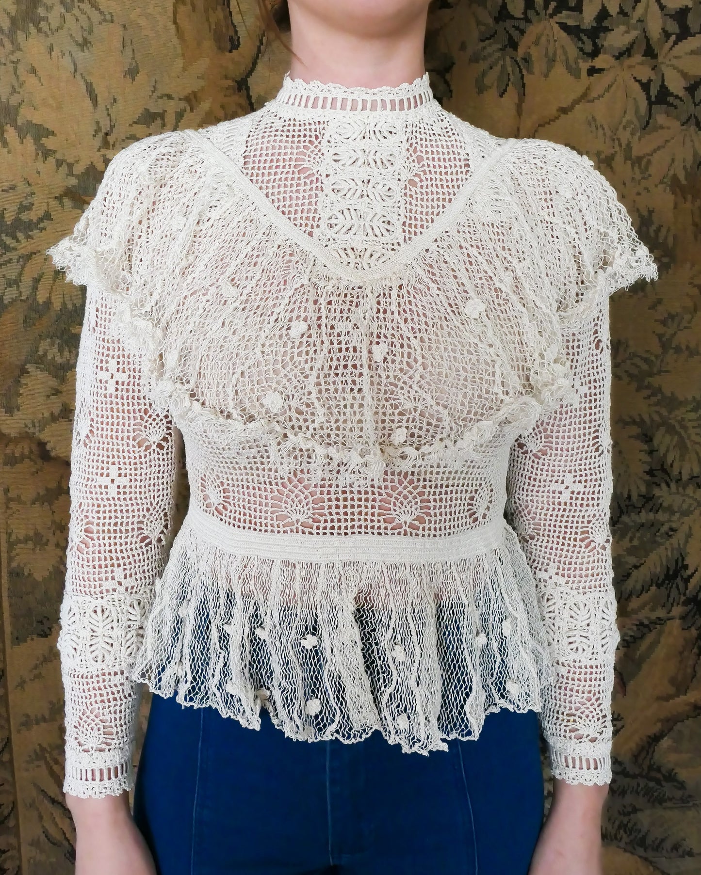 A Lim's original crochet top from the 1980s. Slightly thicker threads were used to crochet the body of the top, and very fine threads give the ruffled parts a lightweight, feminine touch. High Victorian neckline, a beautiful, intricate trim on the sleeves and chest, and a fitted waist and flared hem to create a flattering silhouette. The top is reversible and can be worn with the buttons going down the front or back. This is truly one-of-a-kind, vintage, and our last available piece left! Natural color.