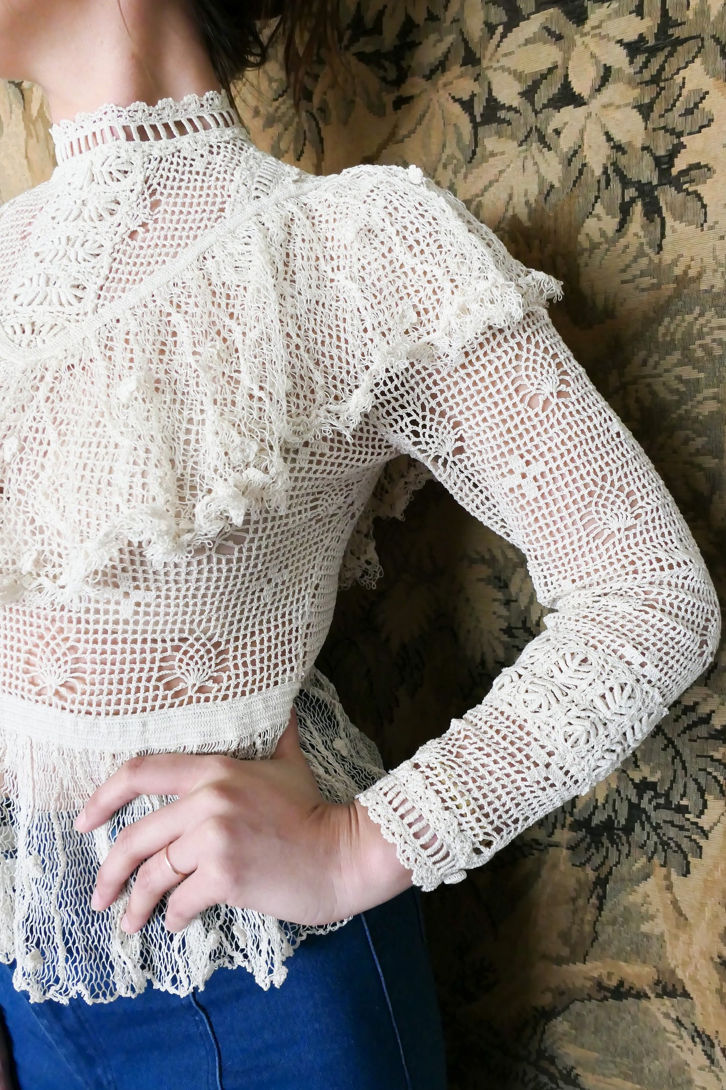 Closeup view of Lim's crochet Victorian style top with ruffles. Detailed crochet work around the forearm and sleeve hem. Natural color.