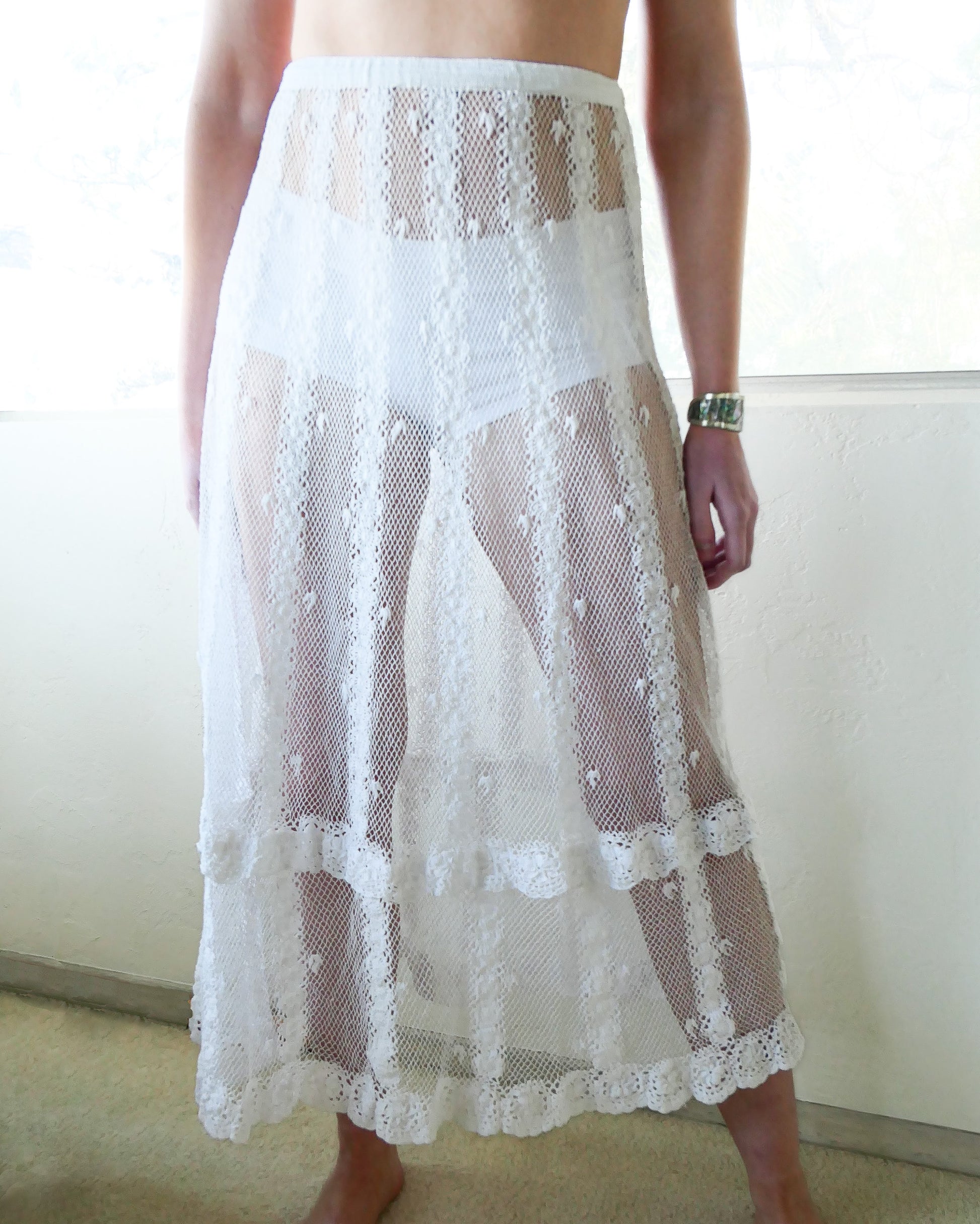 A delicate mesh crocheted skirt with vertical stripes composed of interconnected pinwheel-like circles. The skirt comes with a comfortable fitting elastic waistband and has a slim fit at the hips that tapers out gradually towards the hem. The two-tiered hem adds extra length to the dress. Perfect as a beach coverup! Pair it with sandals or heels and a basic white tank top or camisole.