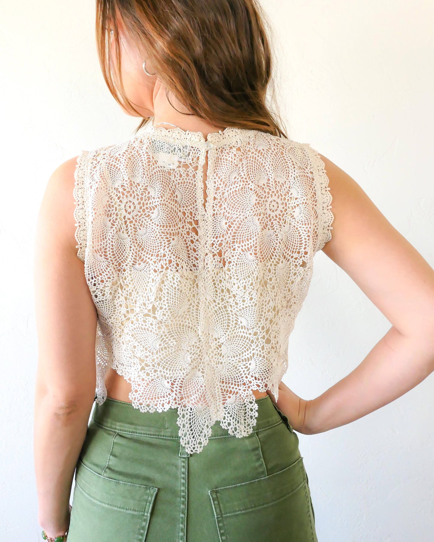 Back view of natural colored crochet top. An ultra casual, hip, and boho-chic crop tank top made with interconnected flower doilies reminiscent of the white lotus, which symbolizes peace, tranquility, and calmness. Lace trim at the collar and sleeve.