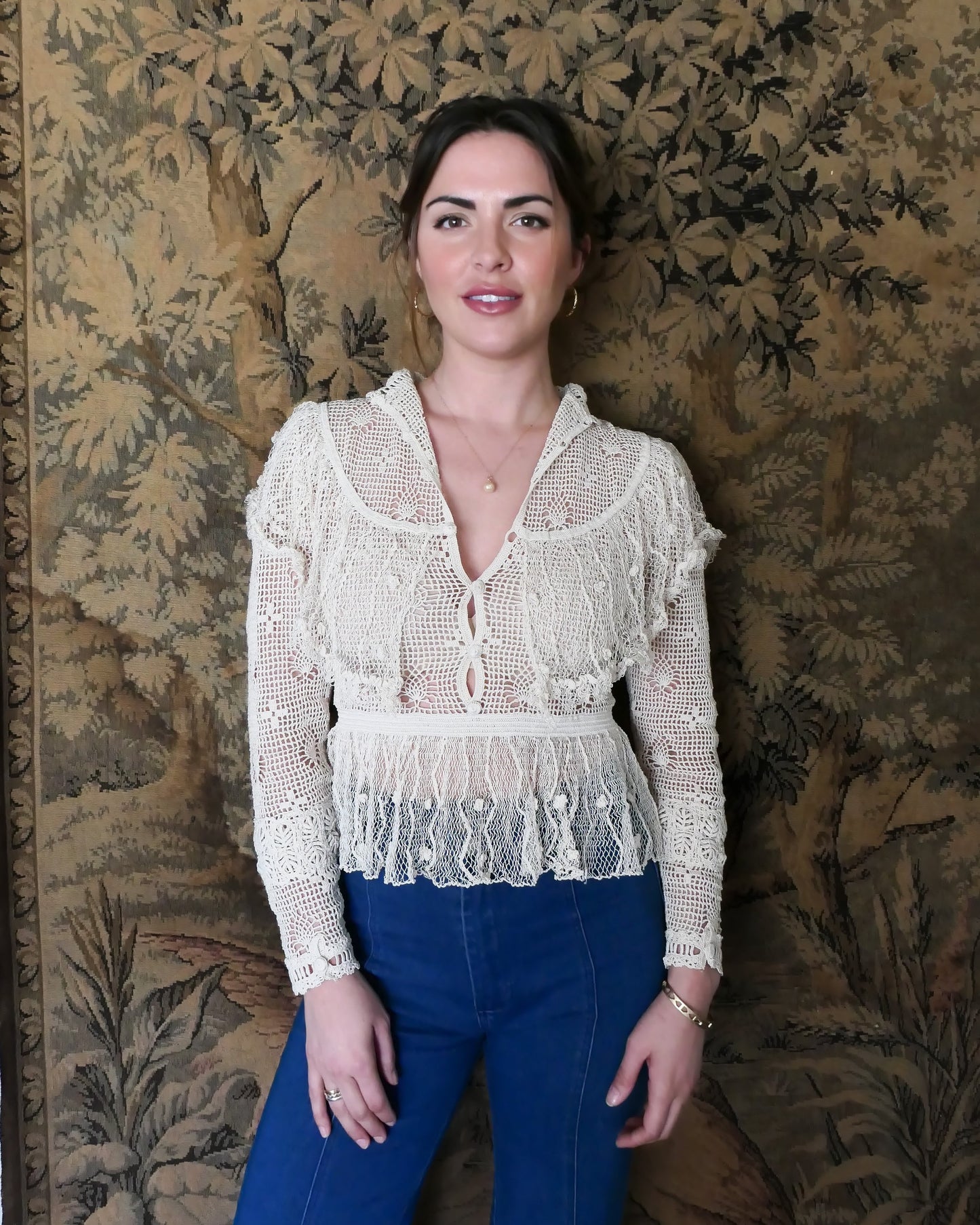 Photo of model wearing the top with buttons going up the front. Lim's original crochet top from the 1980s. Slightly thicker threads were used to crochet the body of the top, and very fine threads give the ruffled parts a lightweight, feminine touch. High Victorian neckline, a beautiful, intricate trim on the sleeves and chest, and a fitted waist and flared hem to create a flattering silhouette. The top is reversible and can be worn with the buttons going down the front or back. T