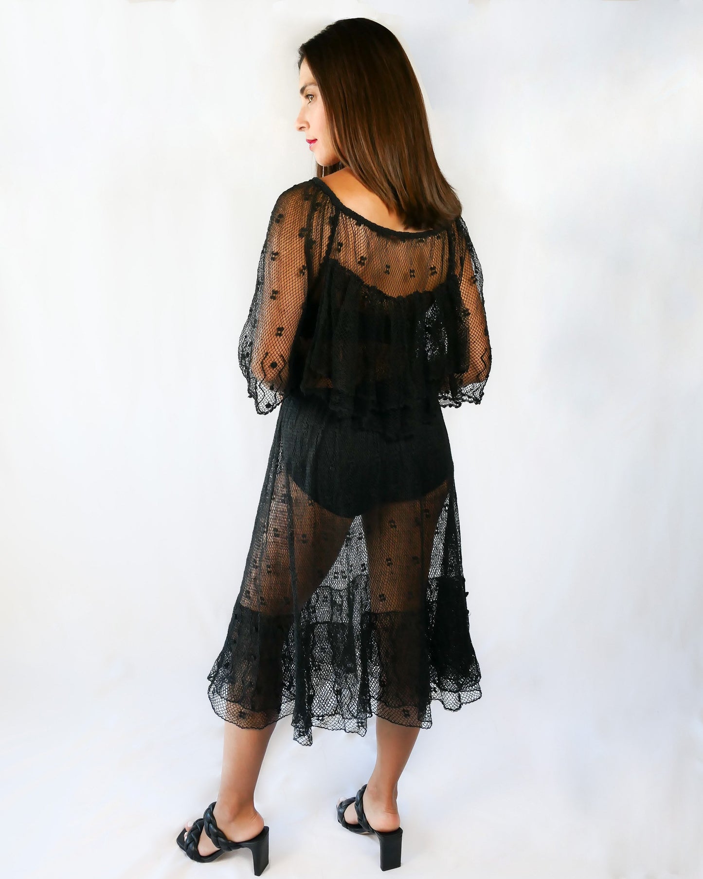 Back view of dress. Get some Oohs and Aahs with this one-of-a-kind black sheer crochet party dress! We combined our vintage Lim's crochet pieces to make this flirty, sensual dress with double semi-ruffle layers all around the front and back collar as well as at the hems. The dress has a wide crew neck and 3/4 length angel sleeves. The crochet is stretchable and gives.