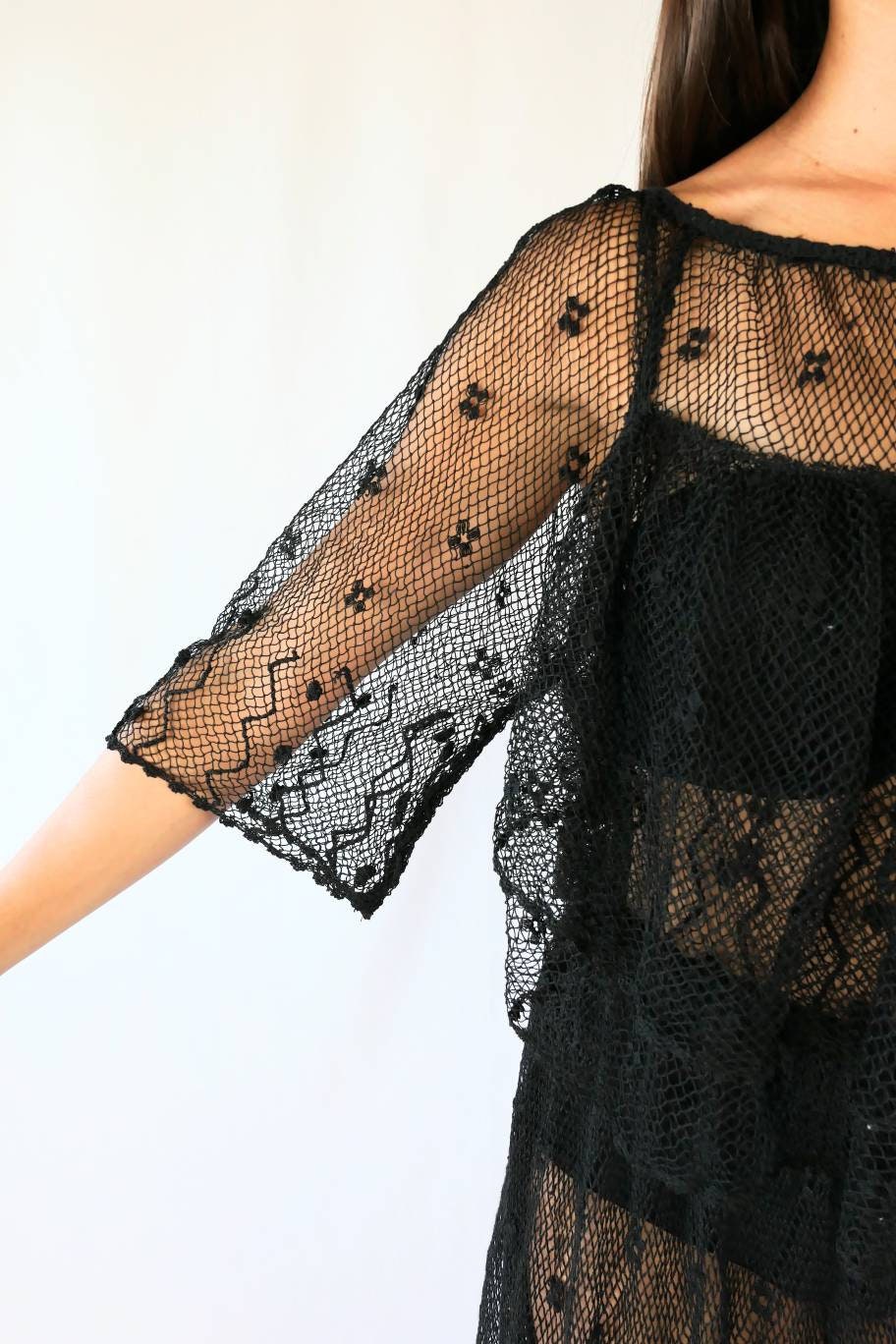 Closeup view of 3/4 length angel sleeves. Get some Oohs and Aahs with this one-of-a-kind black sheer crochet party dress! We combined our vintage Lim's crochet pieces to make this flirty, sensual dress with double semi-ruffle layers all around the front and back collar as well as at the hems. The dress has a wide crew neck and 3/4 length angel sleeves. The crochet is stretchable and gives.