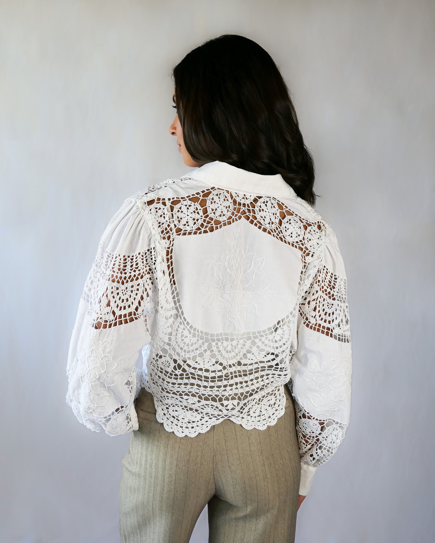 Back view, with rose motif embroidered onto the back of the top. An almost-cropped, lightweight shirt using our vintage Lim's crochet and embroidered cotton fabric, with puff sleeves for a romantic twist. Pair it with high-waisted jeans for casual days, or try it with a flowing midi skirt or wide-legged trousers to dress it up.