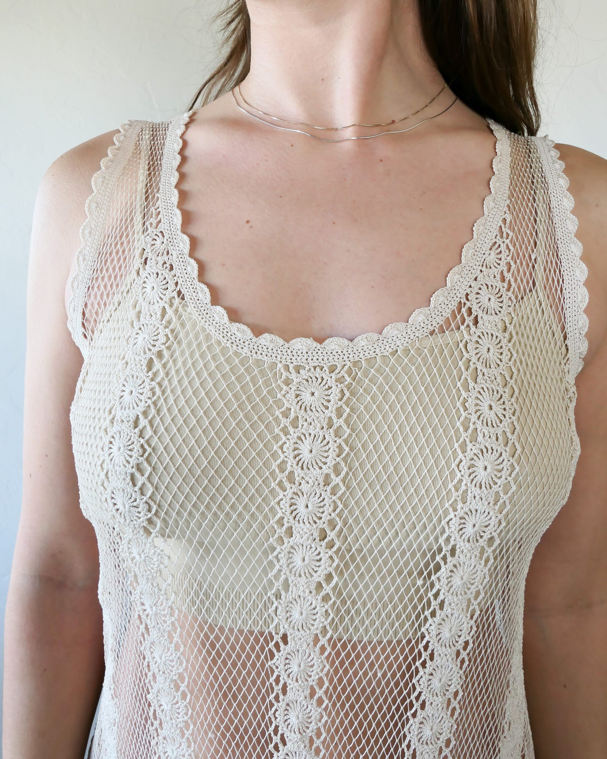 Closeup of front of dress. A classic Lim's crochet fishnet tank maxi dress in Natural with vertical stripes composed of connected pinwheel-like circles. Versatile, lightweight, and an easy pullover dress that is reversible and can be worn with the buttons in the front or back. Perfect as a beach coverup, with boots and a cowgirl hat for that boho chic appeal or worn with a neutral slip and heels for a more sophisticated look.  Size: Small to medium  Measurements:  Bust 32"- 36" Waist 46" Length 51" Hip 50" 