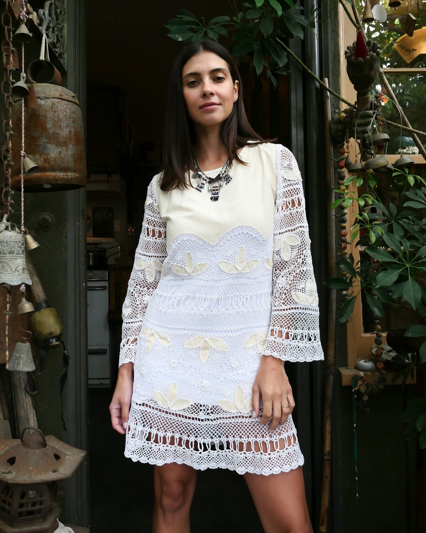 Natural raw silk and artisan hand crochet detail intermix in this mini dress with flared bell sleeves and a comfortable fit. This boho chic dress zips up the back, tapers in at the waist, and is perfect as a beach coverup or a highlight to your vintage wardrobe. Pair it with sandals, or sass it up with cowboy boots and a bold, vintage necklace. Colors: Natural color raw silk and white crochet