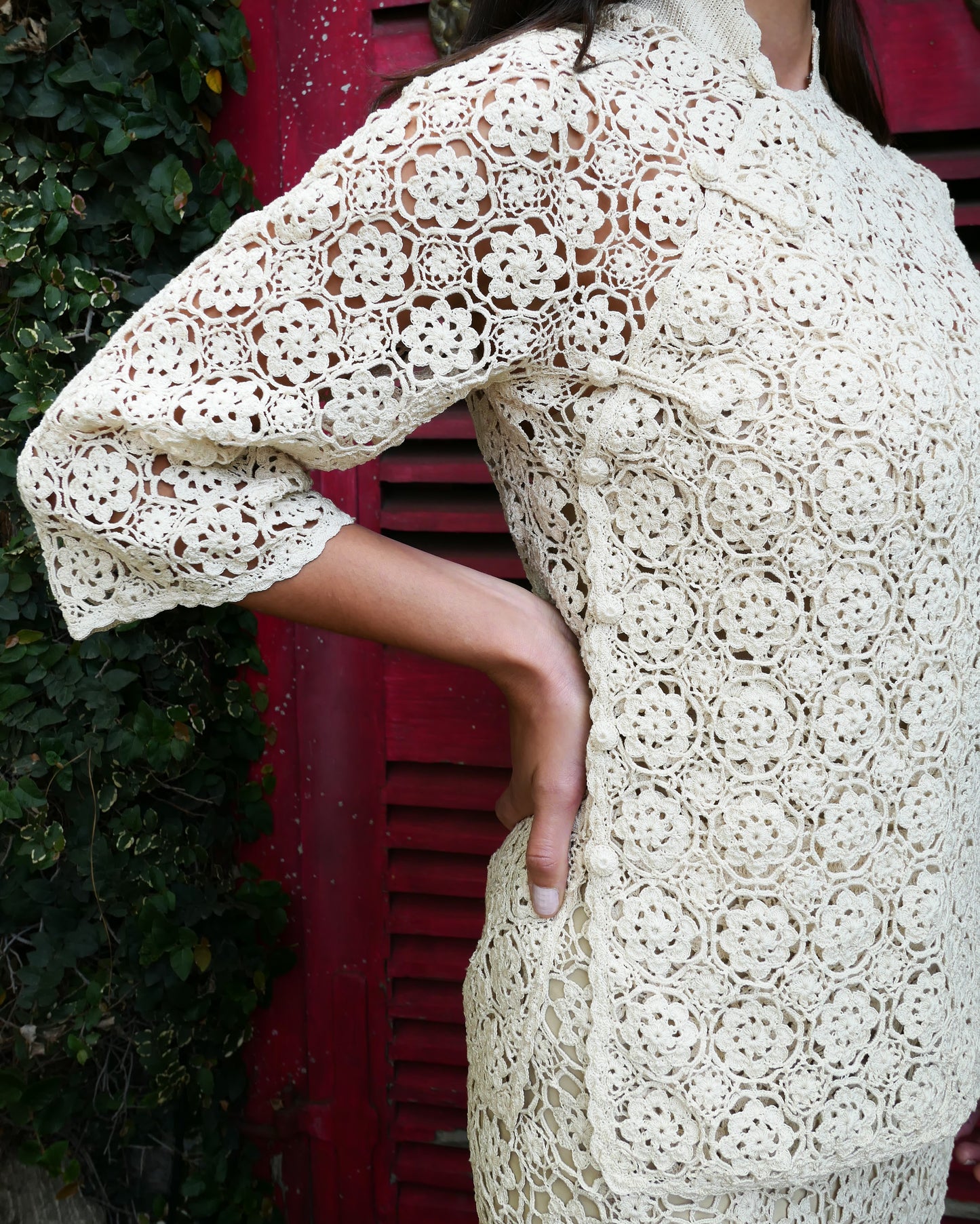 Closeup side view. An intricately hand crocheted top and skirt set reminiscent of the traditional Chinese Qipao, with its high mandarin collar, traditional knotted buttons that run along the front and side of the top, and the side slits that run up either side of the skirt. Simple, refined, beautiful, and one of our classic Lim's Vintage bestsellers. Color: Natural