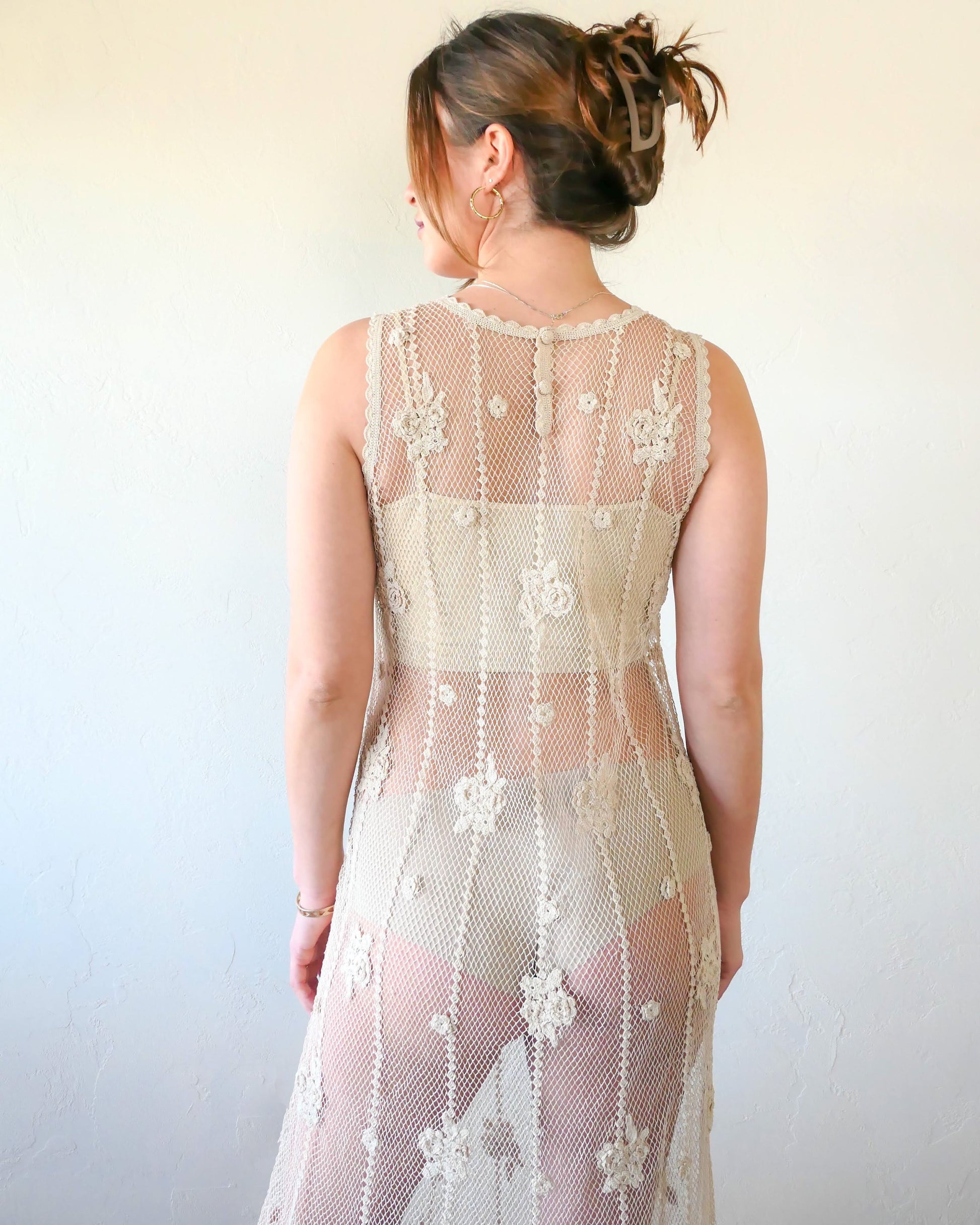 Back view. A classic Lim's crochet fishnet tank maxi dress in Natural with vertical stripes and dainty floral clusters throughout. Versatile, lightweight, and an easy pullover dress that is reversible and can be worn with the buttons in the front or back. Perfect as a beach coverup, with boots and a cowgirl hat for that boho chic appeal or worn with a neutral slip and heels for a more sophisticated look. Size: Fits Small to Medium