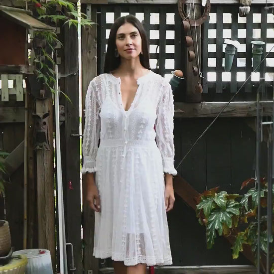 Video of model wearing Lim's Vintage cottage core crochet midi length dress.  Sheer hand crocheted dress with beautiful detail.  Long sleeves with ruffle border at the wrist. Buttons up the front or back and is reversible.