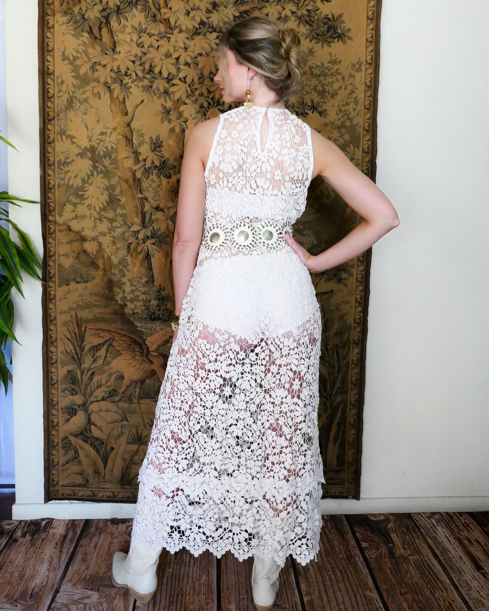 An easy pullover tank maxi dress in white, made with one of our signature Lim's Vintage hand crocheted fabrics that has a delicate floral and leaf motif throughout. The bottom of the dress has a double tiered hem, which adds length to the dress. Wear it with a chunky belt, white boots, and a simple white slip or bralette and bikini shorts on your next special outing.  