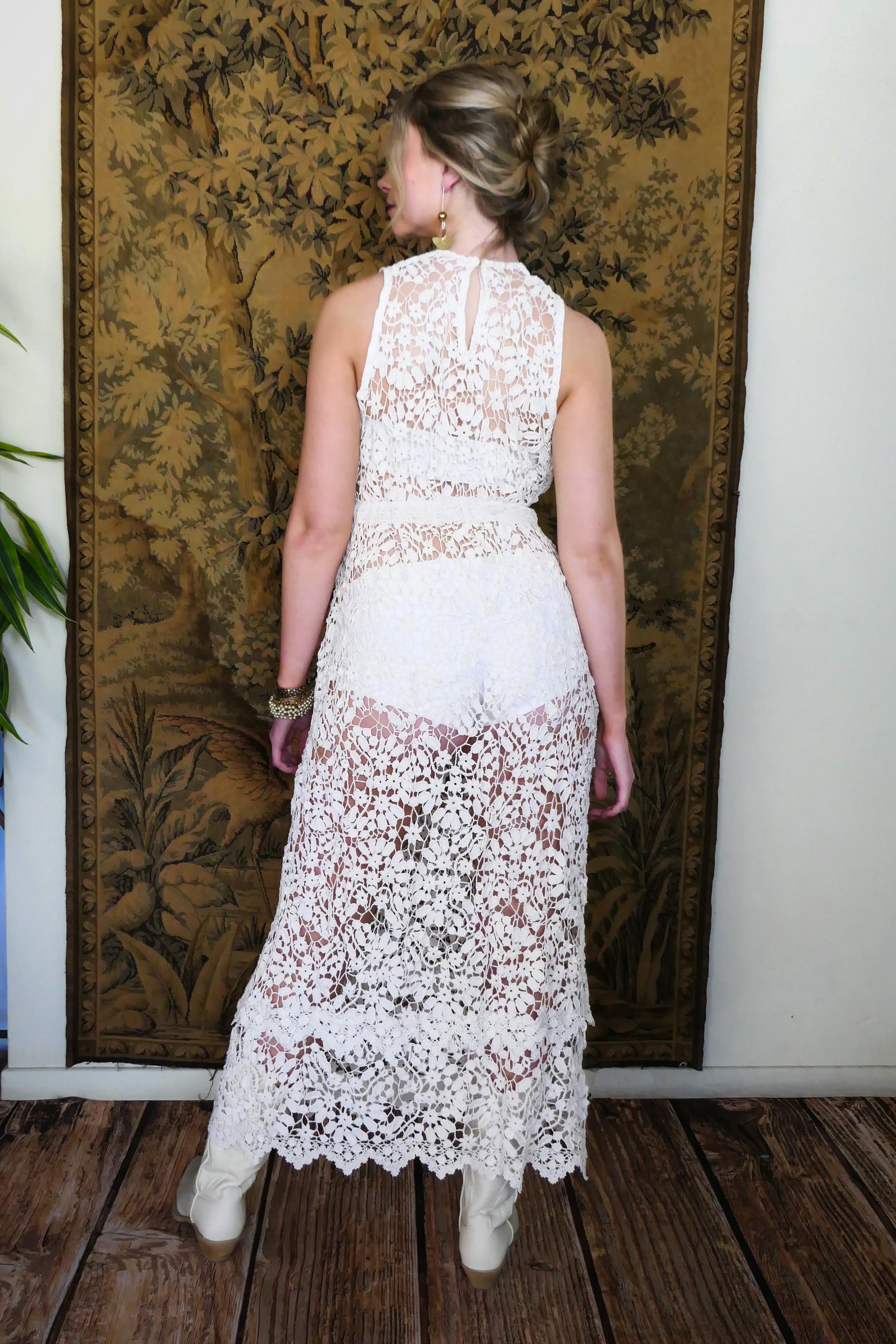 Back view of dress. An easy pullover tank maxi dress in white, made with one of our signature Lim's Vintage hand crocheted fabrics that has a delicate floral and leaf motif throughout. The bottom of the dress has a double tiered hem, which adds length to the dress. Wear it with a chunky belt, white boots, and a simple white slip or bralette and bikini shorts on your next special outing.  