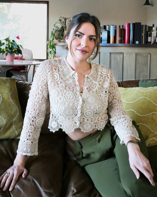 Natural colored crochet crop cardigan. A versatile and boho chic hand crocheted cropped cardigan sweater with a unique, repeating kaleidoscope-like floral pattern throughout. Dress it down with a pair of jeans and sandals, or dress it up with neutral colored wide leg pants, heels, and a pair of vintage dangly earrings.