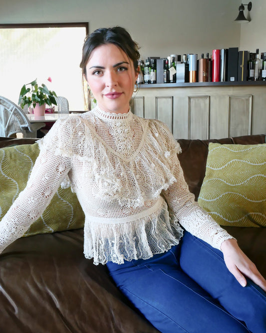 A Lim's original crochet top from the 1980s. Slightly thicker threads were used to crochet the body of the top, and very fine threads give the ruffled parts a lightweight, feminine touch. High Victorian neckline, a beautiful, intricate trim on the sleeves and chest, and a fitted waist and flared hem to create a flattering silhouette. The top is reversible and can be worn with the buttons going down the front or back. This is truly one-of-a-kind, vintage, and our last available piece left! Natural color.