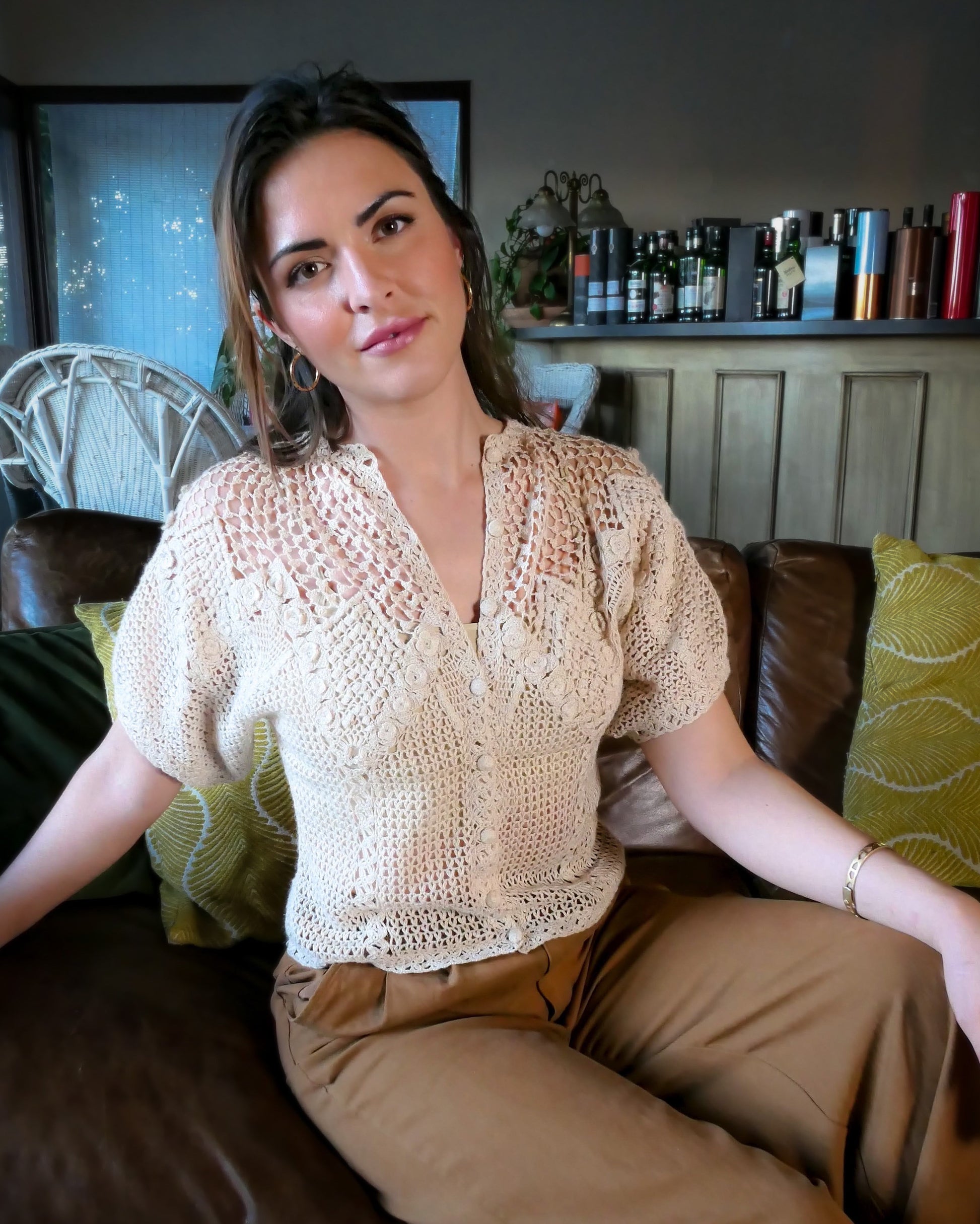 A classic Lim's Vintage hand crocheted button down top with a beautiful zig zag pattern on both the front and back, with lighter stitching around the chest and shoulders to bring a sense of lightness and space to the neckline. Petite flower buds sprout up from and accent the edges of the zig zag. This natural color top is versatile, comfortable, and adds a beautiful vintage accent to your wardrobe.