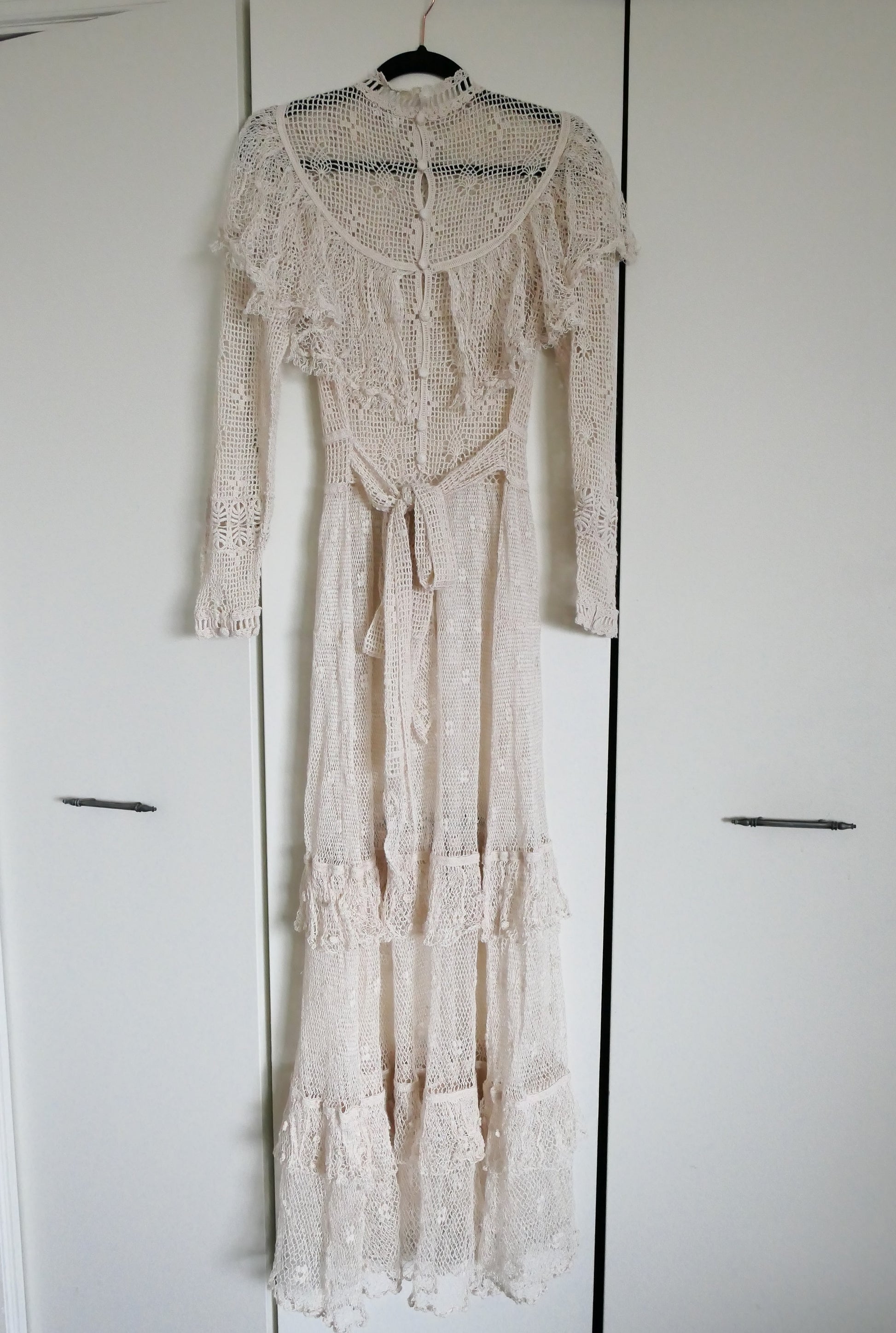 Our one-of-a-kind Lim's original hand crocheted maxi dress from the 1980s, worn by Jane Fonda and once even copied by a famous designer (who shall not be named here) and placed in a major fashion magazine ad. We have only two originals of this dress left in Small and Medium sizes.  Ruffles around the collar line and a two-tiered ruffle at the bottom hem add a boho chic, feminine touch.  The dress is reversible and can be worn with the buttons going up the front or back of the dress.
