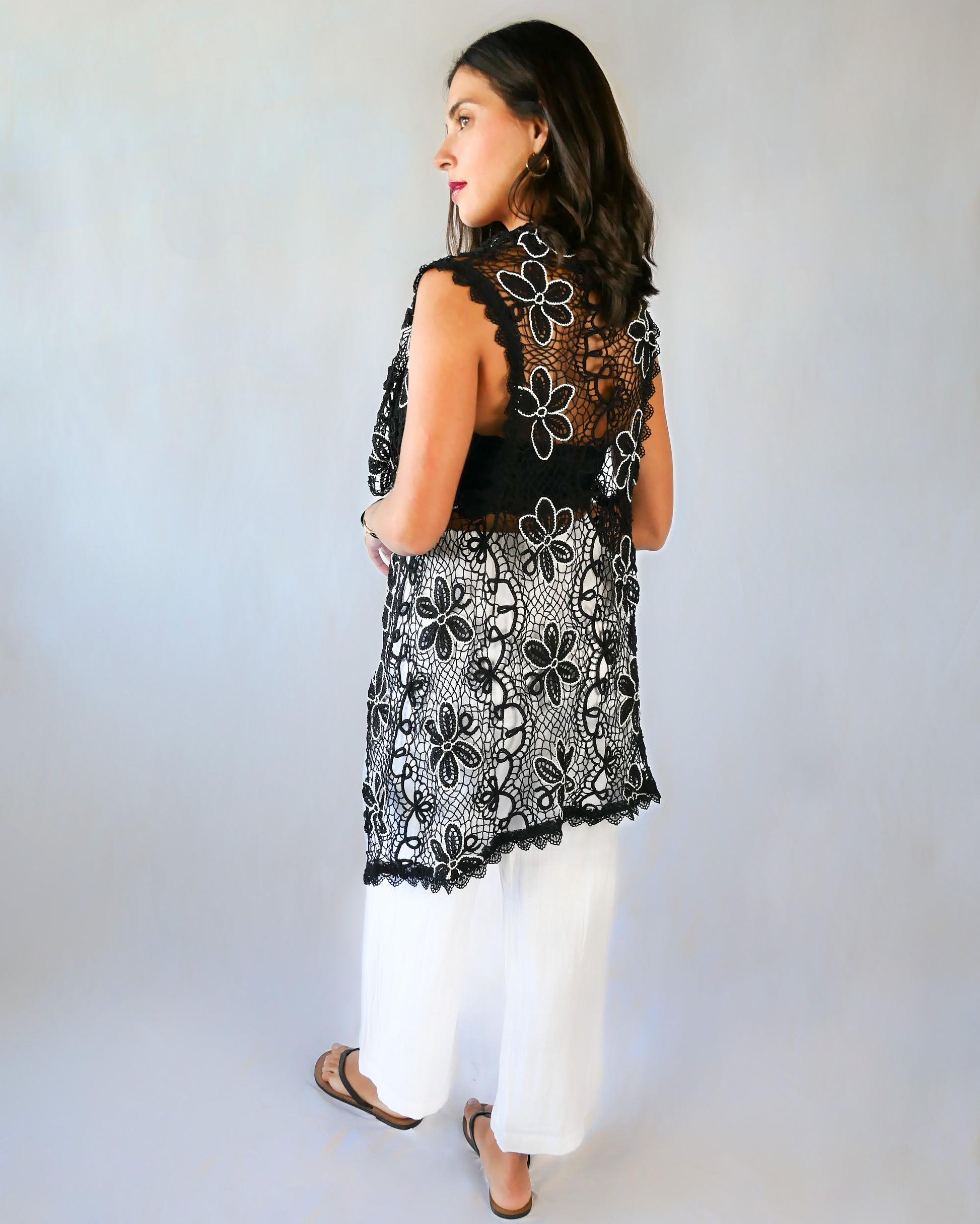 A One Size tie-up hand crocheted long vest with a playful black and white daisy flower motif throughout. Pair it with a strapless bikini bra, a pair of wide-leg trousers, and heels or sandals depending on your mood.  Made with original Lim's Vintage crochet fabric. 